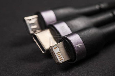 Diferentes enchufes de carga USB sobre fondo oscuro. USB Tipo C, Micro USB, USB relámpago.