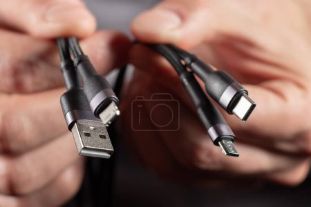 Foto de Manos que sostienen el cable del adaptador universal del conector USB al micro USB, mini-USB y otros conectores. - Imagen libre de derechos