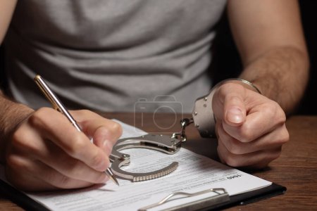 Photo for Tax evasion, crime and fraud concept. Man in handcuffs filling out tax form Income tax return documents and handcuffs - Royalty Free Image