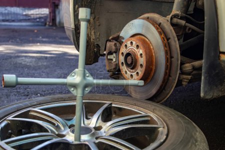Photo for Car lifted by scissor jack without wheel outdoors, closeup. Tire puncture, - Royalty Free Image
