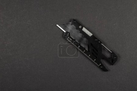Téléchargez les photos : Couteau tactique de papeterie avec une lame sur un fond sombre. - en image libre de droit