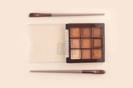 Make-up palette and brush on beige background. Professional multicolor eye shadow make-up palette. Cosmetic products.