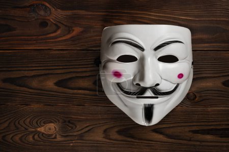 Foto de Dnipro. Ucrania 30 de enero de 2024: Máscara Vendetta sobre fondo de madera. Esta máscara es un símbolo bien conocido para el grupo hacktivista en línea Anónimo. - Imagen libre de derechos