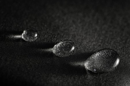 Rain water droplets on black fiber waterproof fabric.