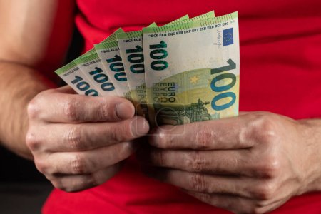Mano masculina sosteniendo billetes de 100 euros de cerca.