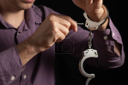 Großaufnahme der Hand von Polizeibeamten Handschellen an männlichen Angeklagten entriegeln Hand für Hand, Fokus auf Schlüsselfessel.