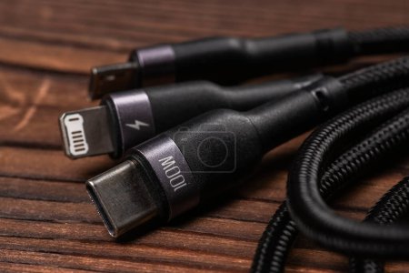 Different USB charging plugs on wooden background. USB Type C, Micro USB, Usb lightning.