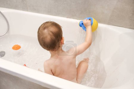 Foto de El niño juega en el baño con una regadera, lápices, juegos en el baño, bañar a los niños - Imagen libre de derechos