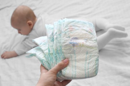 Photo for Mother holds baby diapers against the background of a child in the background. Change of diapers. - Royalty Free Image