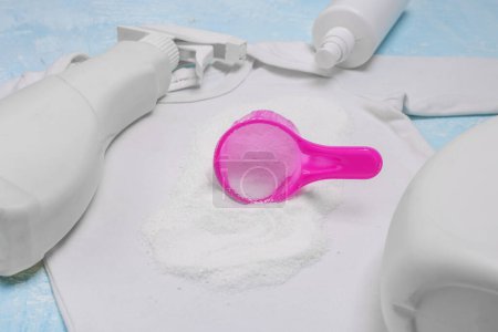 Photo for Pink plastic cup with powder on white baby body. Bleach. Stain remover. Loose dry powder for removing stains. Different types of stain removers. Dirty clothes.Close up - Royalty Free Image
