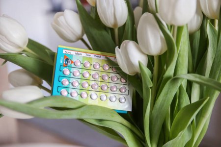 Photo for Birth control pills on the background of white tulips. unwanted pregnancy. Monthly routine. Methods of contraception. hormone therapy - Royalty Free Image