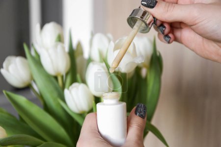 Photo for Day cream with dropper on the background of white tulips. Personal care, professional cosmetics. The secret of youth - Royalty Free Image