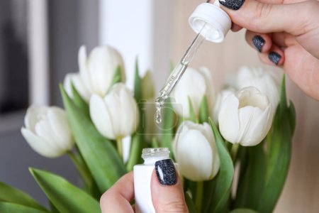 Photo for Face serum on the background of white tulips. Personal care, professional cosmetics. The secret of youth - Royalty Free Image