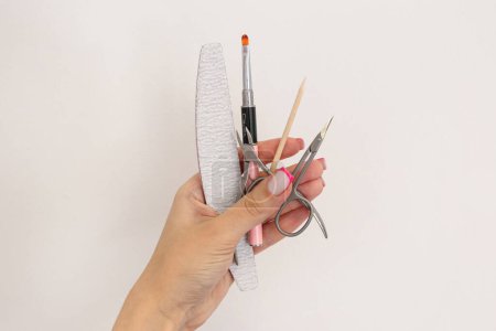 Téléchargez les photos : Gros plan des mains de la femme tenant des outils de manucure sur un fond blanc - en image libre de droit