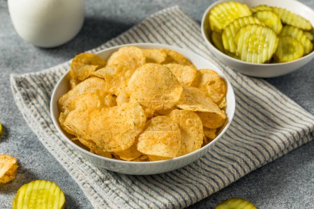 Foto de Homemade Flavored Dill Pickle Potato Chips in a Bowl to Eat - Imagen libre de derechos