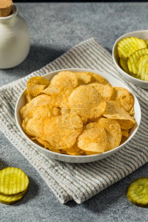 Photo for Homemade Flavored Dill Pickle Potato Chips in a Bowl to Eat - Royalty Free Image