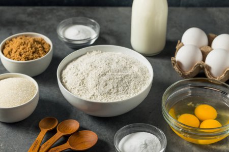 Foto de Organic Raw Baking Ingredients with Flour Sugar Milk and Eggs - Imagen libre de derechos