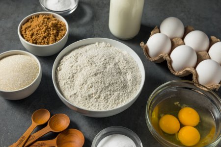 Foto de Organic Raw Baking Ingredients with Flour Sugar Milk and Eggs - Imagen libre de derechos