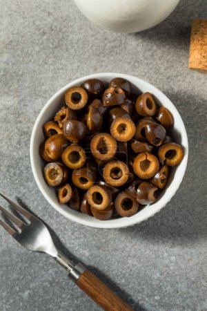 Téléchargez les photos : Olives brunes noires tranchées bio dans un bol - en image libre de droit