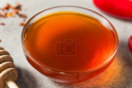 Téléchargez les photos : Miel chaud épicé cru biologique dans un bol avec trempette - en image libre de droit