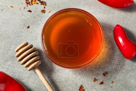 Foto de Miel caliente picante cruda orgánica en un tazón con la cacerola - Imagen libre de derechos