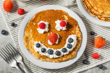 Photo for Sweet American Smiley Face Breakfast Pancakes with Whipped Cream and Berries - Royalty Free Image