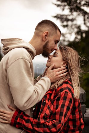 Téléchargez les photos : Jeune homme et femme amoureux debout sur la terrasse d'observation quelque part dans les montagnes regardant le paysage - en image libre de droit