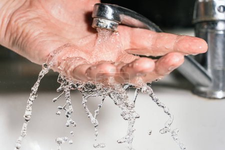 A swift stream of clean water pours into the palm of your hand in the shower, streams and splashes of water wash away bacteria and viruses. Open hand under a strong jet of water. Ecological problems