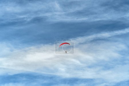 Téléchargez les photos : Un parapente s'élève dans le vaste ciel bleu, incarnant la liberté et l'aventure. Cette image peut être un concept pour explorer, prendre des risques et profiter de la vie des possibilités illimitées - en image libre de droit