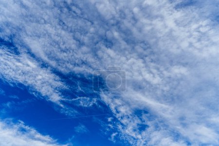 Serene sky with wispy clouds and a jet trail, capturing the essence of freedom and tranquility. Ideal for themes of nature, peace, and travel
