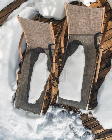 Des chaises longues drapées de neige sur une terrasse en bois, signalant la fin des hivers règnent. Une métaphore parfaite pour le changement, le renouvellement et le calme avant le printemps