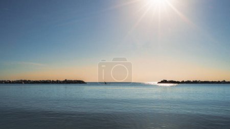 Ein einsames Kajak paddelt durch eine riesige Weite ruhigen Ozeans unter einem pulsierenden Sonnenuntergang Himmel, vermittelt ein Gefühl der Einsamkeit, Abenteuer und Verbindung mit der Schönheit der Natur