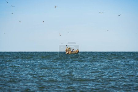 Photo for Morning stillness at sea, where a lone fisherman boat and the cries of seagulls sing the clear blue sky the eternal bond between man and nature and Italy maritime traditions - Royalty Free Image