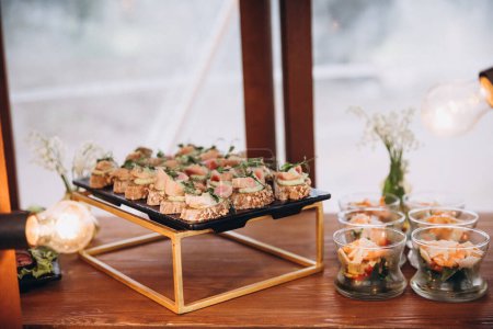 Foto de Food. A party. Plates with snacks for guests on wooden table - Imagen libre de derechos