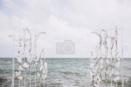 Téléchargez les photos : Orchidée blanche fleurs arc de mariage sur le rivage - en image libre de droit