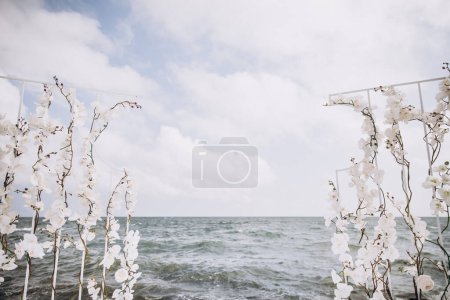 Photo for White orchid flowers wedding arch on seashore - Royalty Free Image
