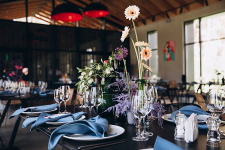 Photo for Banquet tables decorated with flowers, dishes on the tables with blue napkins, glasses, colorful flowers - Royalty Free Image