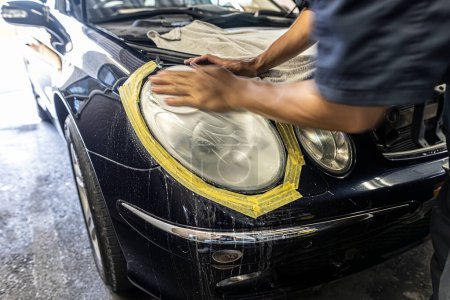 Téléchargez les photos : A mechanic polishes the headlights of a car. - en image libre de droit