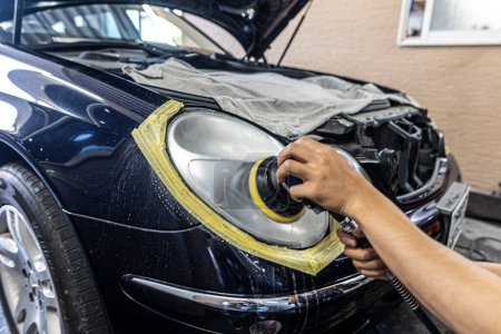 Foto de A mechanic polishes the headlights of a car. - Imagen libre de derechos