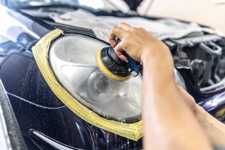 Photo for A mechanic polishes the headlights of a car. - Royalty Free Image