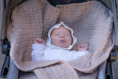Téléchargez les photos : Beau portrait de l'appartenance ethnique mixte adorable Asiatique Caucasien bébé fille de quelques semaines couché sur le chariot de bébé dormir paisiblement portant un chapeau doux dans une nouvelle vie et concept nouveau-né - en image libre de droit