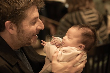 Téléchargez les photos : Portrait de style de vie à l'intérieur de père heureux tenant son nouveau-né petite fille seulement quelques semaines assis sur le café prenant soin de la petite fille fière et joyeuse - en image libre de droit
