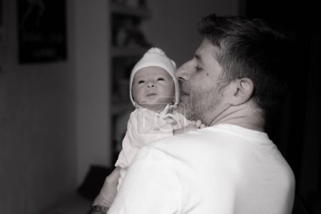 Téléchargez les photos : Portrait de style de vie de l'homme attrayant et heureux tenant sa petite fille dans ses bras comme un père fier dans le concept parental et l'amour en noir et blanc - en image libre de droit