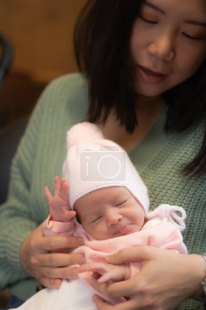 Foto de Joven feliz y atractiva asiática china mujer sosteniendo su adorable bebé recién nacido niña en sus brazos dulce y tierno en crianza y madre amor concepto - Imagen libre de derechos