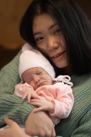 Téléchargez les photos : Jeune femme coréenne asiatique heureuse et attrayante tenant son adorable bébé fille dans ses bras doux et tendre dans le concept d'amour parental et maternel - en image libre de droit
