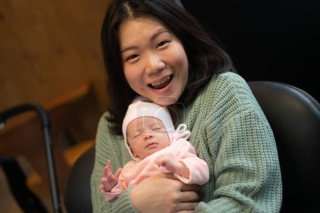 Téléchargez les photos : Jeune femme coréenne asiatique heureuse et attrayante tenant son adorable bébé fille dans ses bras doux et tendre dans le concept d'amour parental et maternel - en image libre de droit