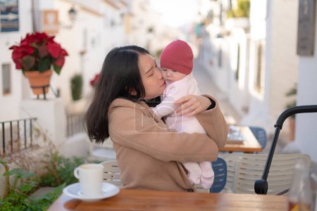 Foto de Joven feliz y hermosa asiática coreana mujer sosteniendo su adorable niña mientras toma café al aire libre en madre hija amor y vinculación concepto - Imagen libre de derechos