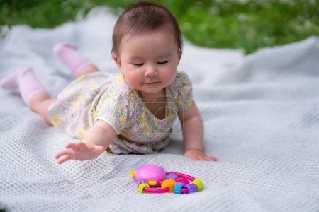 Photo for Adorable and happy baby girl in summer hat embraces the joys of playfulness on a soft blanket playing with little toy. Laughing as she explores the natural wonders of an outdoors city park - Royalty Free Image