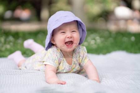 Foto de Adorable y feliz niña en sombrero de verano abraza las alegrías de la alegría en una manta suave. Riéndose mientras explora las maravillas naturales de un parque al aire libre de la ciudad - Imagen libre de derechos