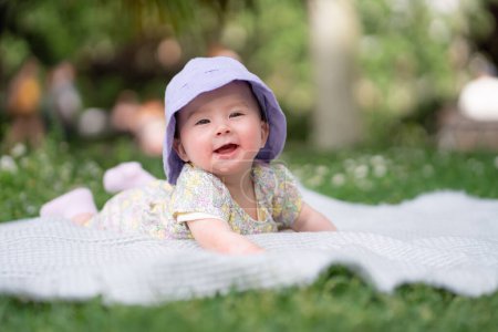 Foto de Adorable y feliz niña en sombrero de verano abraza las alegrías de la alegría en una manta suave. Riéndose mientras explora las maravillas naturales de un parque al aire libre de la ciudad - Imagen libre de derechos